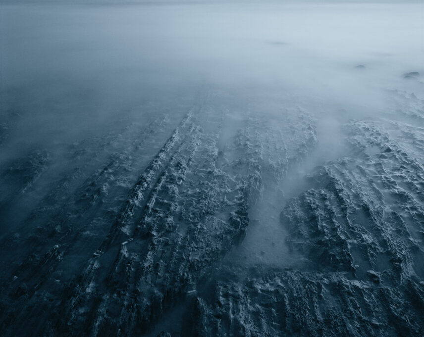 Photograph of a shore in shades of blue and grey