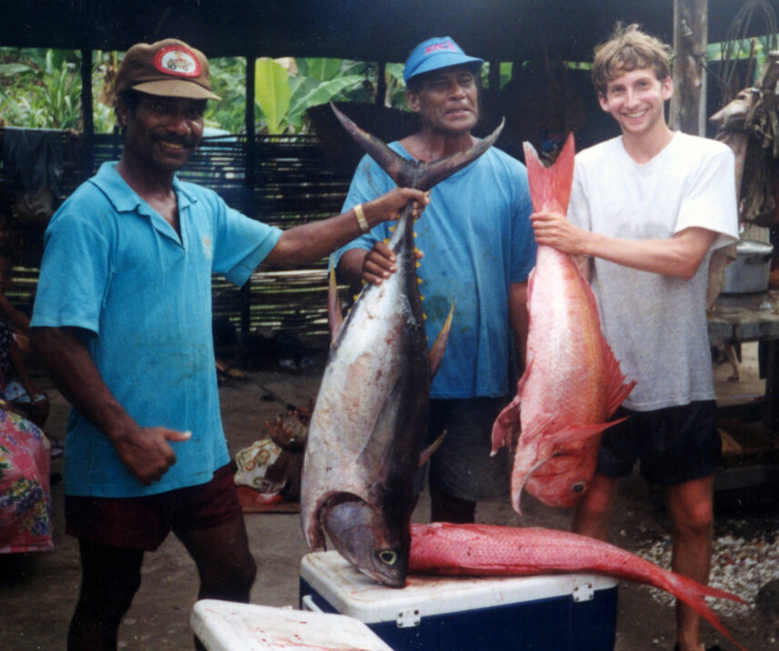 People standing outdoors holding up large fish