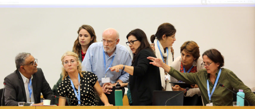 Photo of people standing around a table talking.