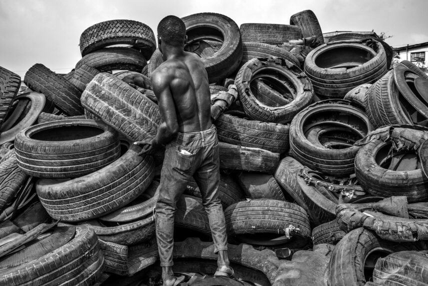 Photograph of a person in front of a pile of tires