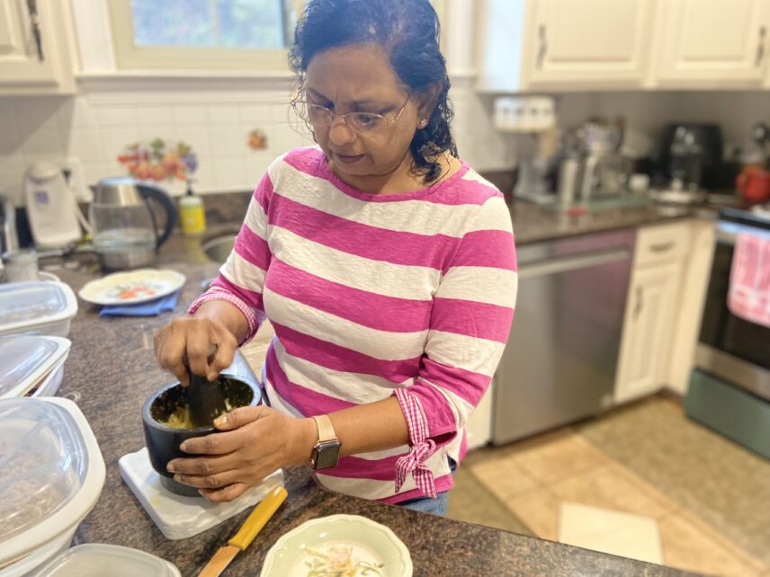 Amutha minces garlic and ginger for her spicy prawn pirattal (shrimp fry).