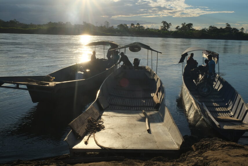 A picture of three longboats gathered at the shore of a riverbank.