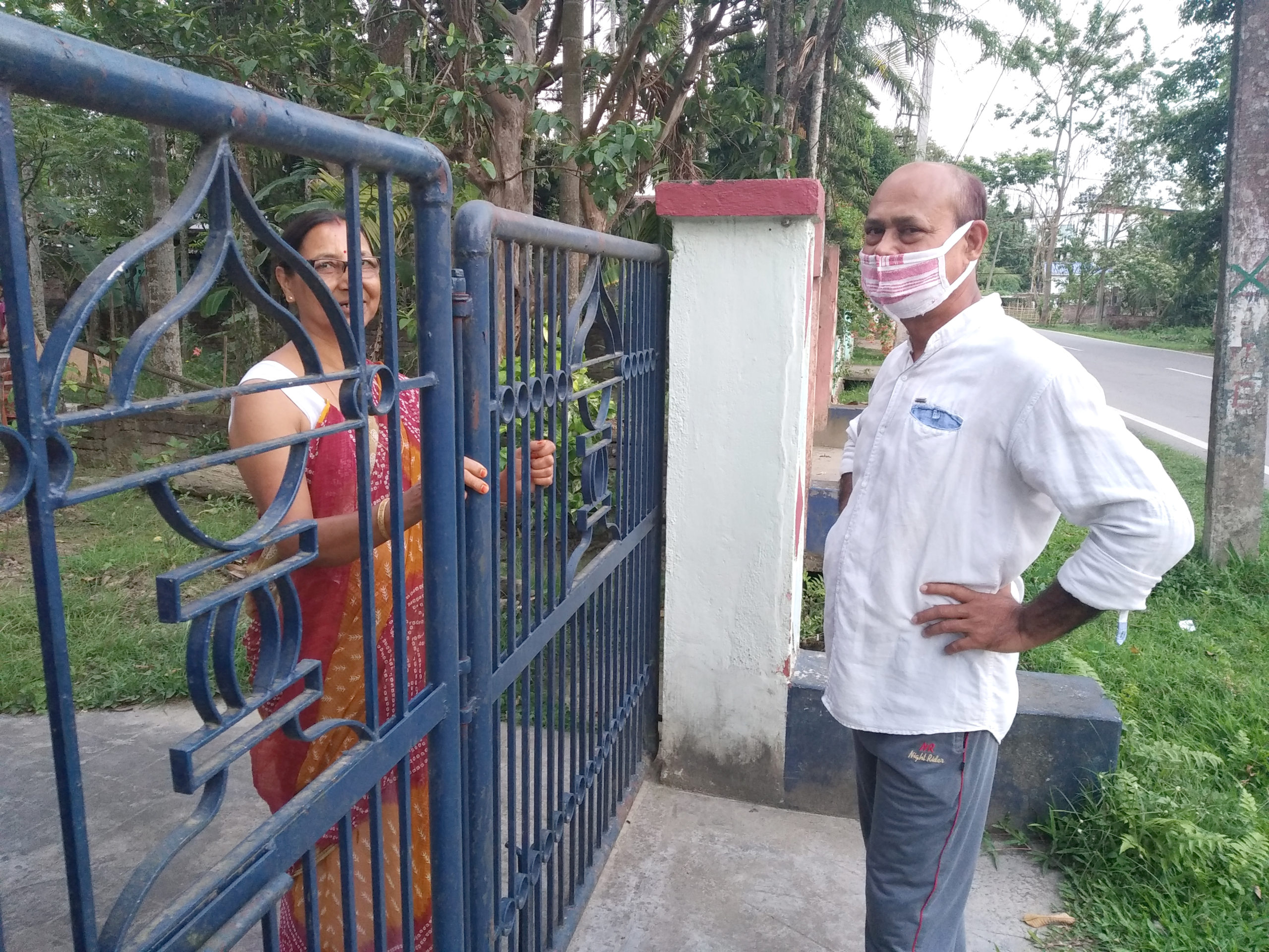 A photograph of two people interacting across a blue gate.