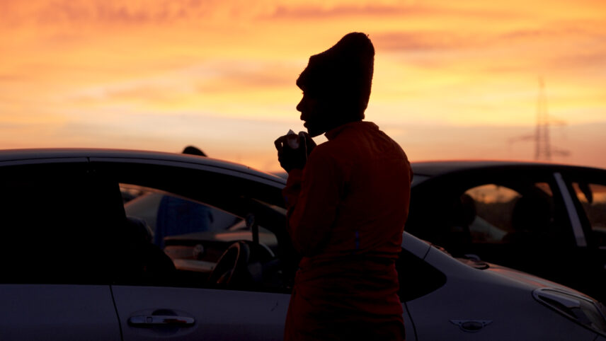Photograph of a person standing beside a car