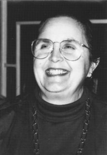 A candid portrait of a woman in glasses with a large smile.