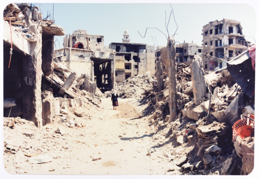 Photograph of a woman walking through a landscape of destruction