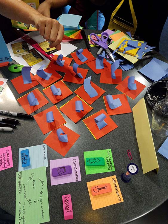 Photograph of a tabletop with paper, sharpies, and other stationery items