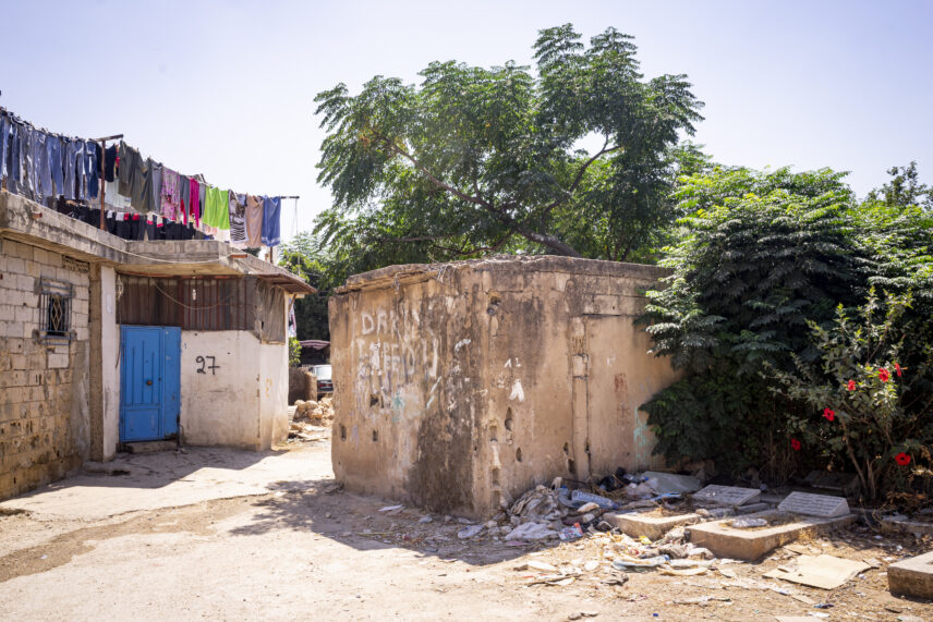 Photograph of two small, worn structures and a few grave plots