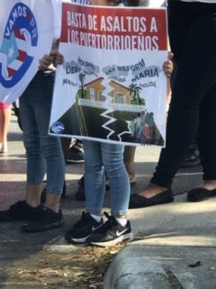 Photo of two people holding up protest signs; their faces cannot be seen.