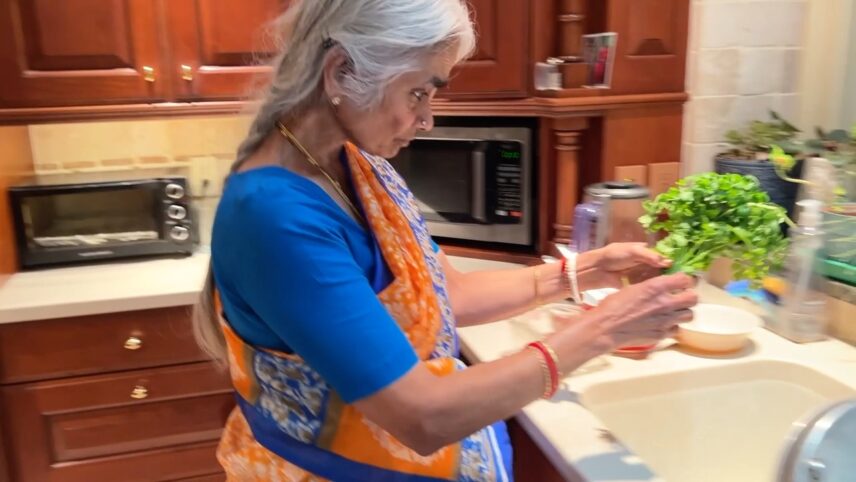 Shakuntala cleans coriander for her rasam, a traditional soup or broth made with tamarind, tomatoes, spices, and herbs.