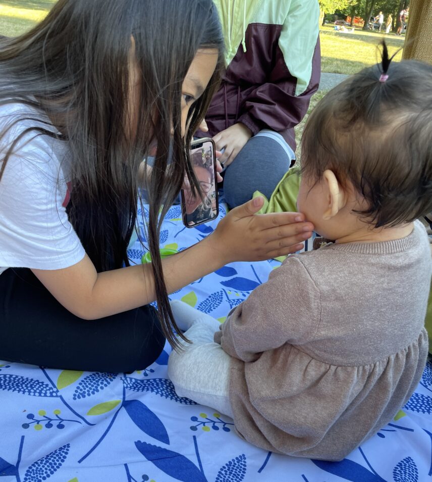 a child holds a smart phone to face towards an infant
