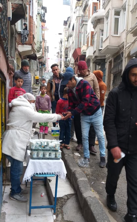 Photograph of people standing in line on a city street.