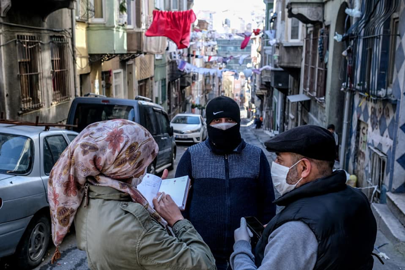Photograph of three people in conversation on a city street.